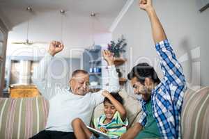 Cheerful family with arms raised siting on sofa