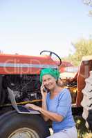 Portrait of happy woman using laptop while talking on mobile phone