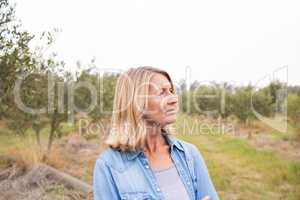 Thoughtful woman standing in olive field