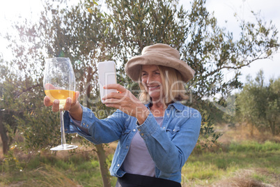 Woman taking a photo of wine glass in olives farm