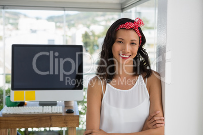 Portrait of smiling businesswoman with arms crossed leaning by wall