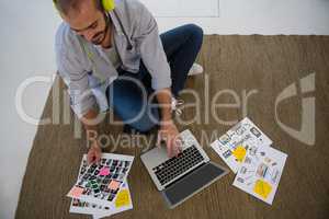 Designer using laptop while sitting on floor at studio