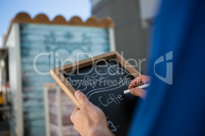 Cropped hand of owner writing menu