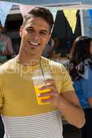 Young man holding juice while standing by food truck