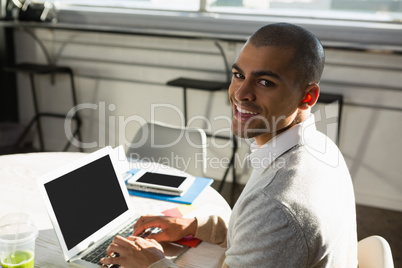 Portrait of businessman using laptop computer while sitting at desk