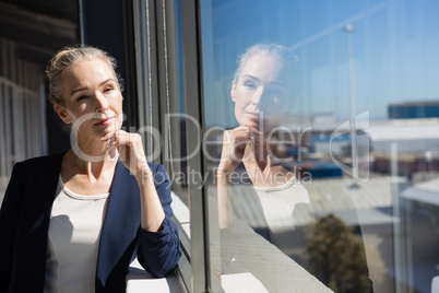 Thoughtful businesswoman looking through window at office