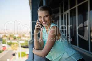 Portrait of happy woman talking on mobile phone in office balcony