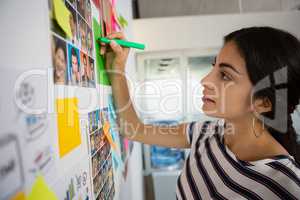 Businesswoman writing on sticky note at office
