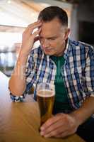 Worried man sitting at bar with glass of beer