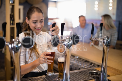 Female bartender filling beer from bar pump