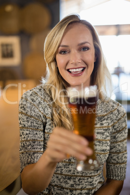 Beautiful woman holding glass of beer at bar counter Beautiful woman holding glass of beer at bar counter