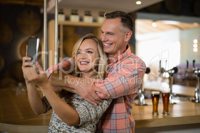 Couple taking selfie on mobile phone in bar