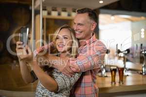 Couple taking selfie on mobile phone in bar