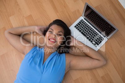 Female executive relaxing with hands behind head on the floor