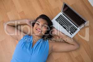 Female executive relaxing with hands behind head on the floor