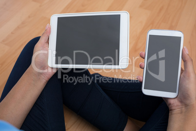 Female executive holding mobile phone and digital tablet