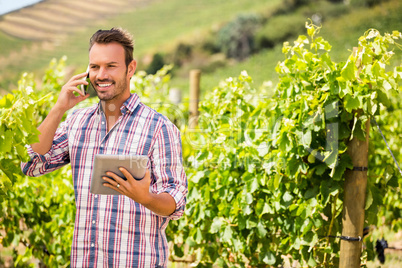 Man looking away while talking on phone at vineyard