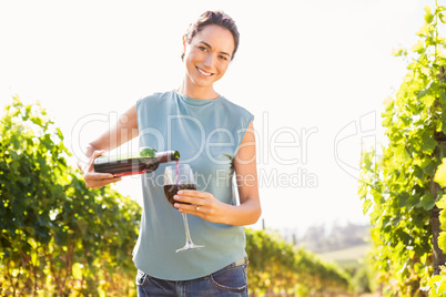 Portrait of smiling woman pouring red wine from bottle in glass