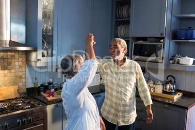 Smiling couple dancing in kitchen at home