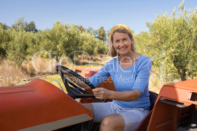 Portrait of happy woman sitting in tractor