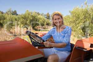 Portrait of happy woman sitting in tractor