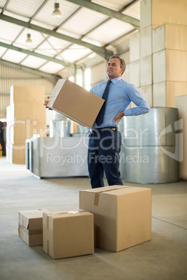 Manager suffering from back pain while holding heavy box