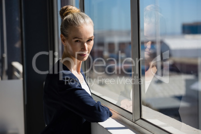 Confident woman standing by window in office