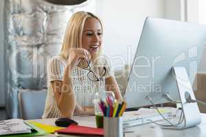 Woman holding eyeglasses at desk in office