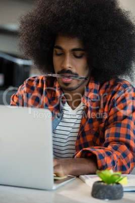 Man with curly hair using laptop at desk in office