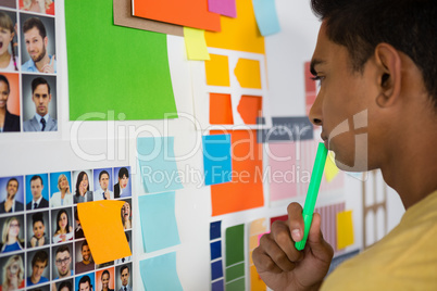 Thoughtful man looking at sticky notes in office