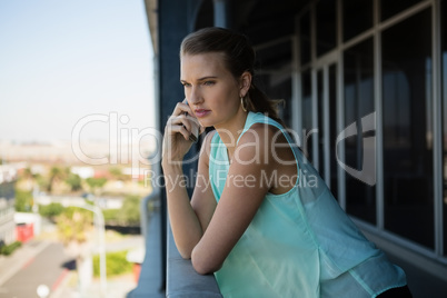 Woman talking on mobile phone in office balcony