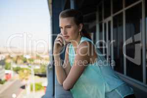 Woman talking on mobile phone in office balcony