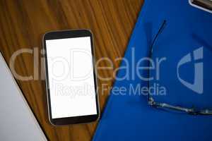 High angle view of phone and clipboard on table in office