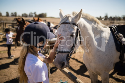 Girl caressing the white horse in the ranch