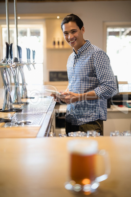 Bar tender holding digital tablet at counter