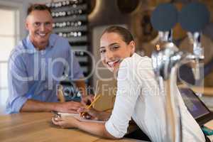 Smiling manager and bartender standing at bar counter
