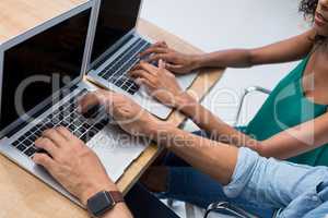 Male and female executives working on laptop at desk