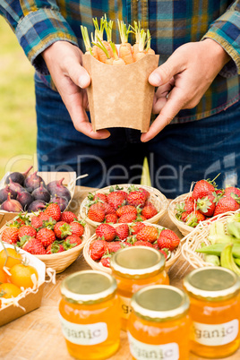 Midsection of man holding carrots over strawberries for sale