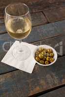 High angle view of  white wine by green olives served in container
