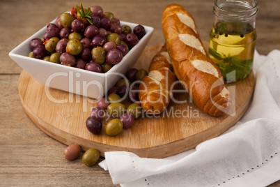 High angle view of olives in container by bread and oil