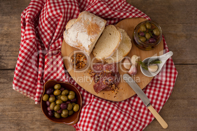 Overhead view of bread and olives with meat on napkin