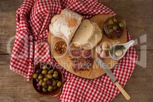 Overhead view of bread and olives with meat on napkin
