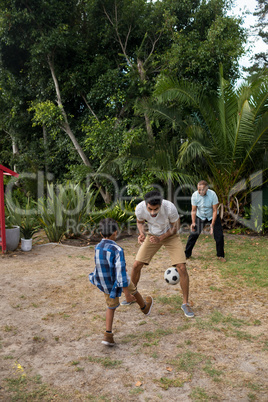 Boy playing soccer with parents on field