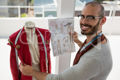 Portrait of smiling designer standing by mannequin