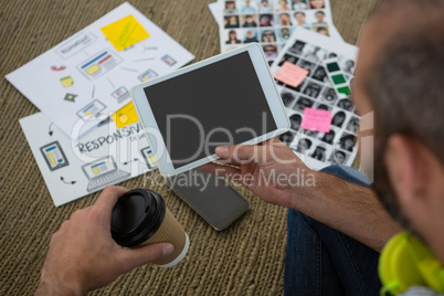 High angle biew of designer holding disposable cup and tablet computer