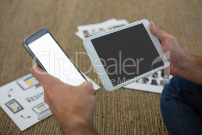 Crpped hands of designer holding mobile phone and digital tablet