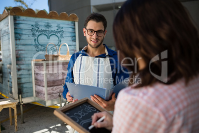 Man looking at coworker writing menu by food truck