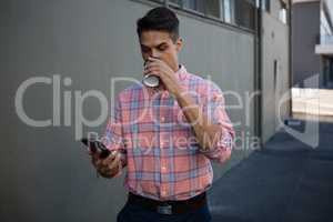 Young man using mobile phone while having drink