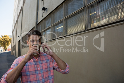 Man having drink while talking on mobile phone