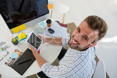 Portrait of graphic designer using tablet computer at desk in studio